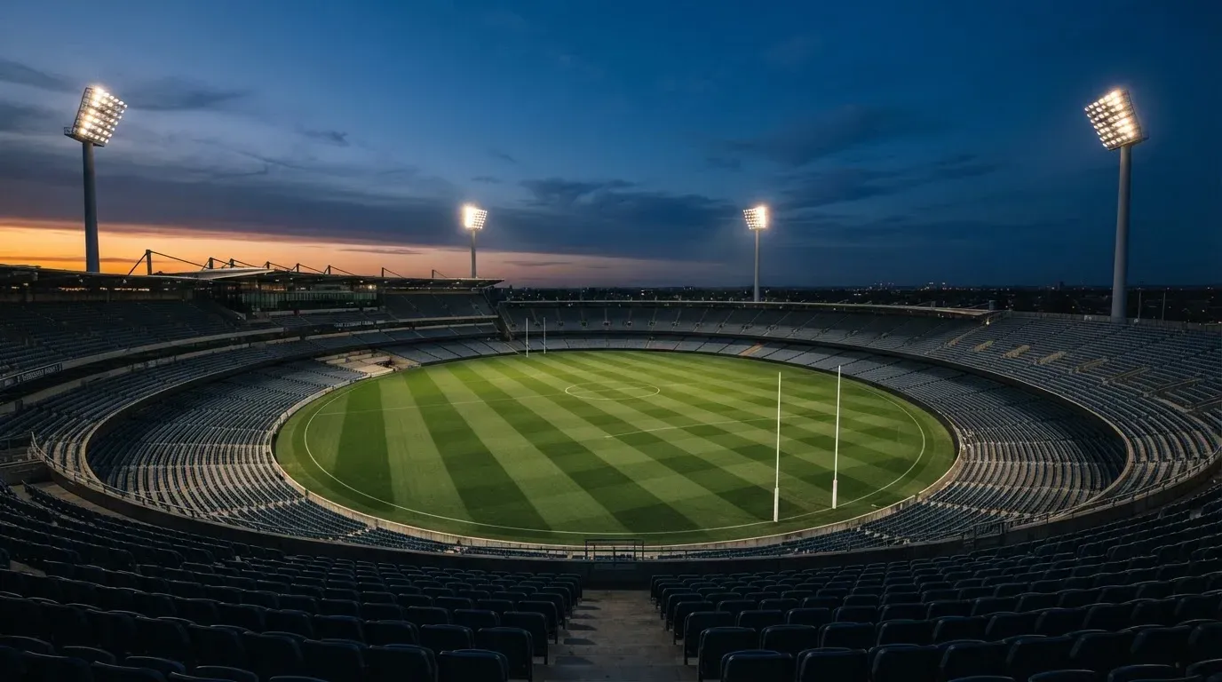An empty football stadium with floodlight masts at dusk