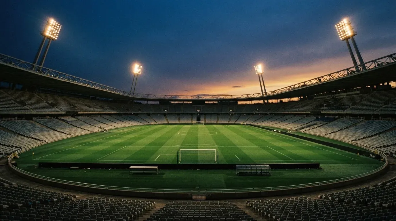 An empty football stadium with floodlight masts at dusk