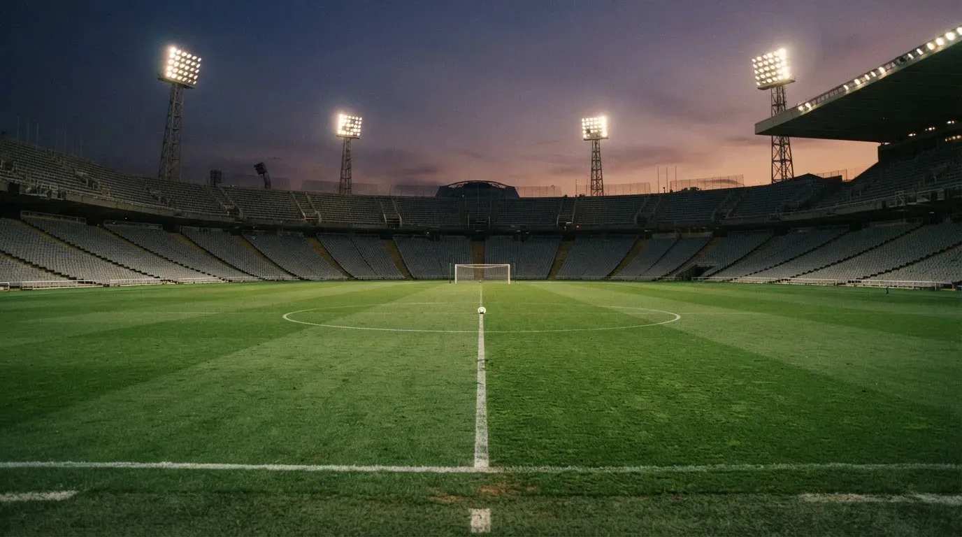An empty football stadium with floodlight masts at dusk