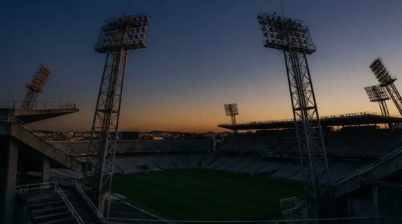 An empty football stadium with floodlight masts at dusk
