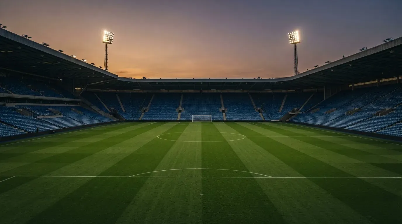An empty football stadium with floodlight masts at dusk