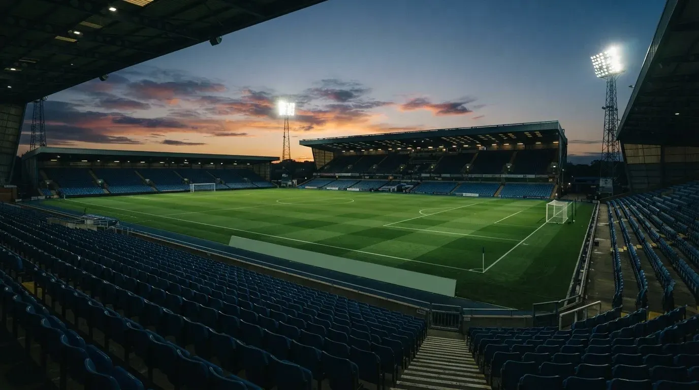 An empty football stadium with floodlight masts at dusk