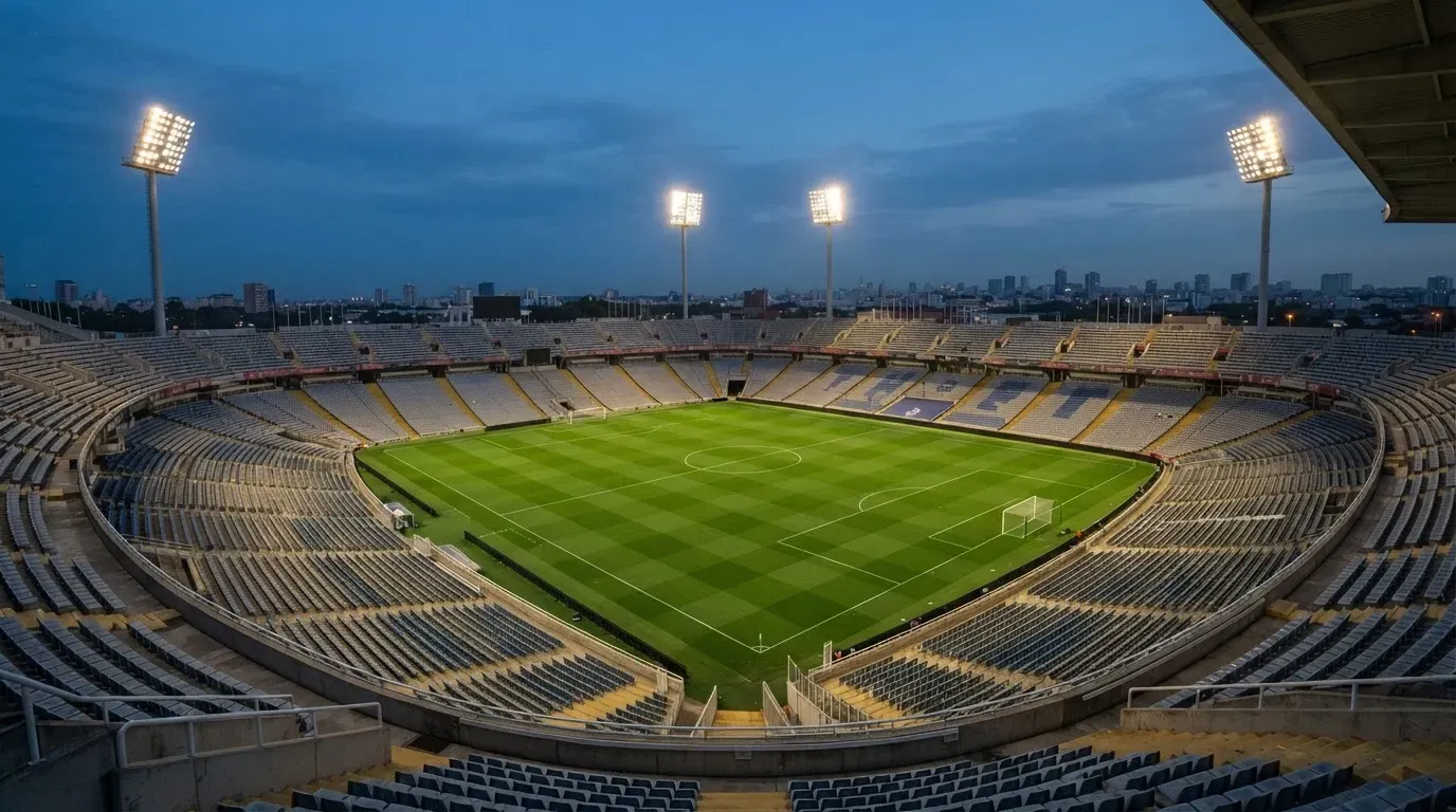 An empty football stadium with floodlight masts at dusk