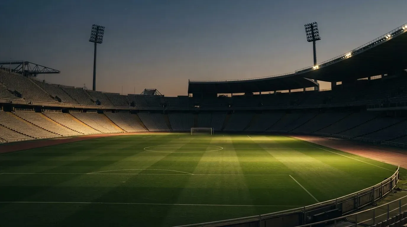 An empty football stadium with floodlight masts at dusk