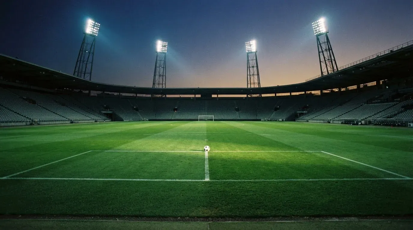 An empty football stadium with floodlight masts at dusk
