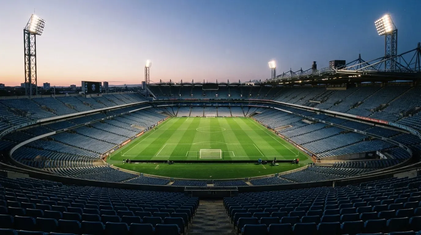 An empty football stadium with floodlight masts at dusk