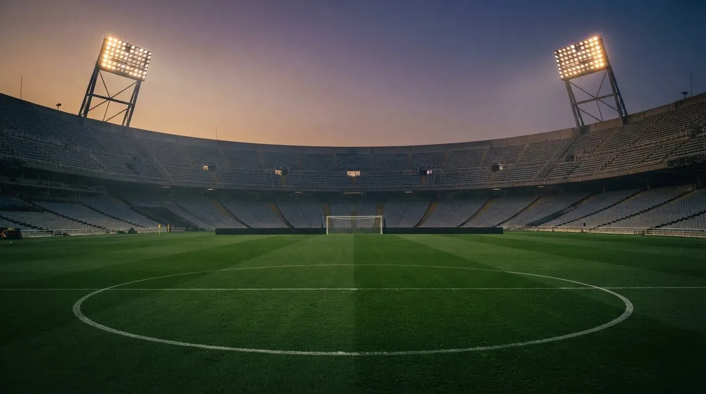 An empty football stadium with floodlight masts at dusk