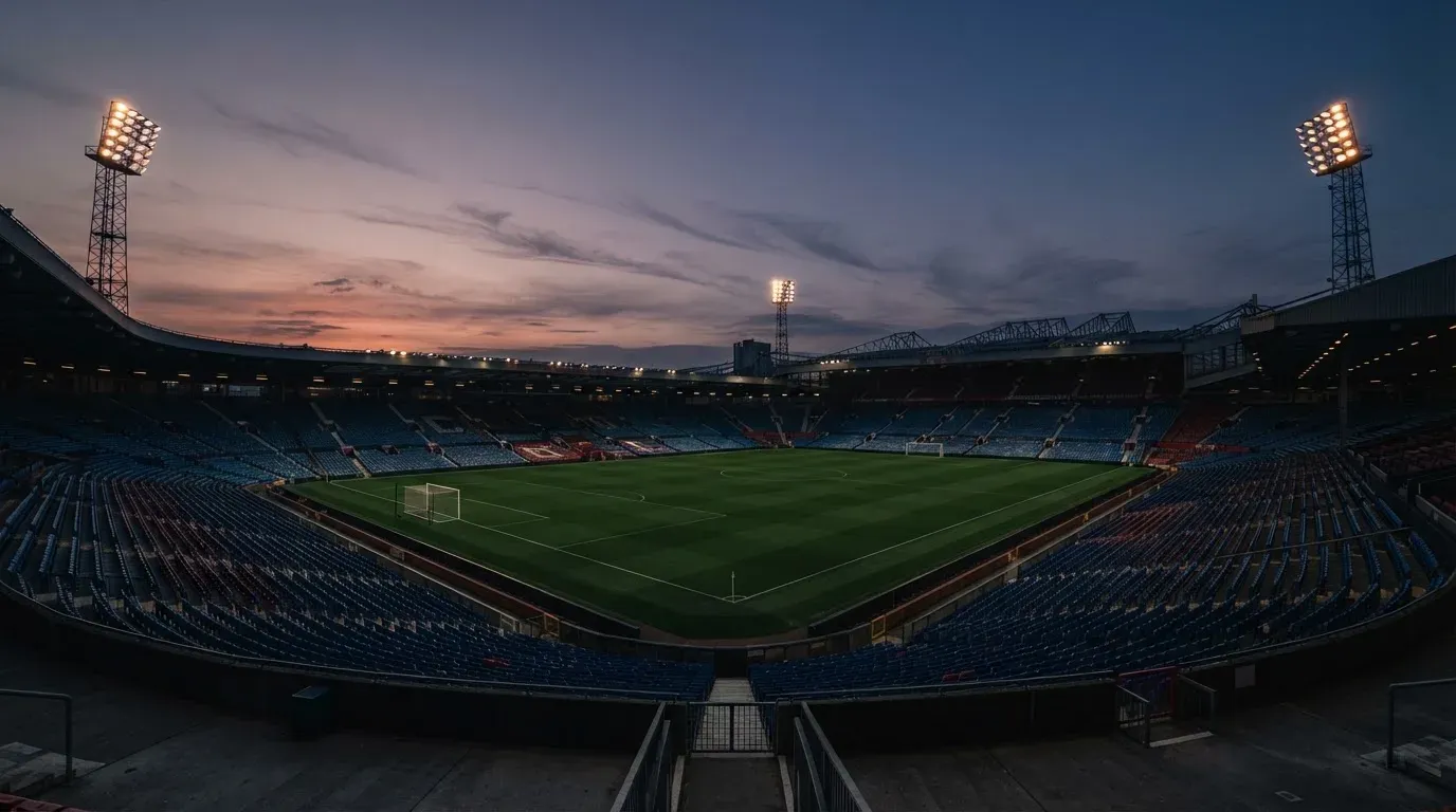 An empty football stadium with floodlight masts at dusk