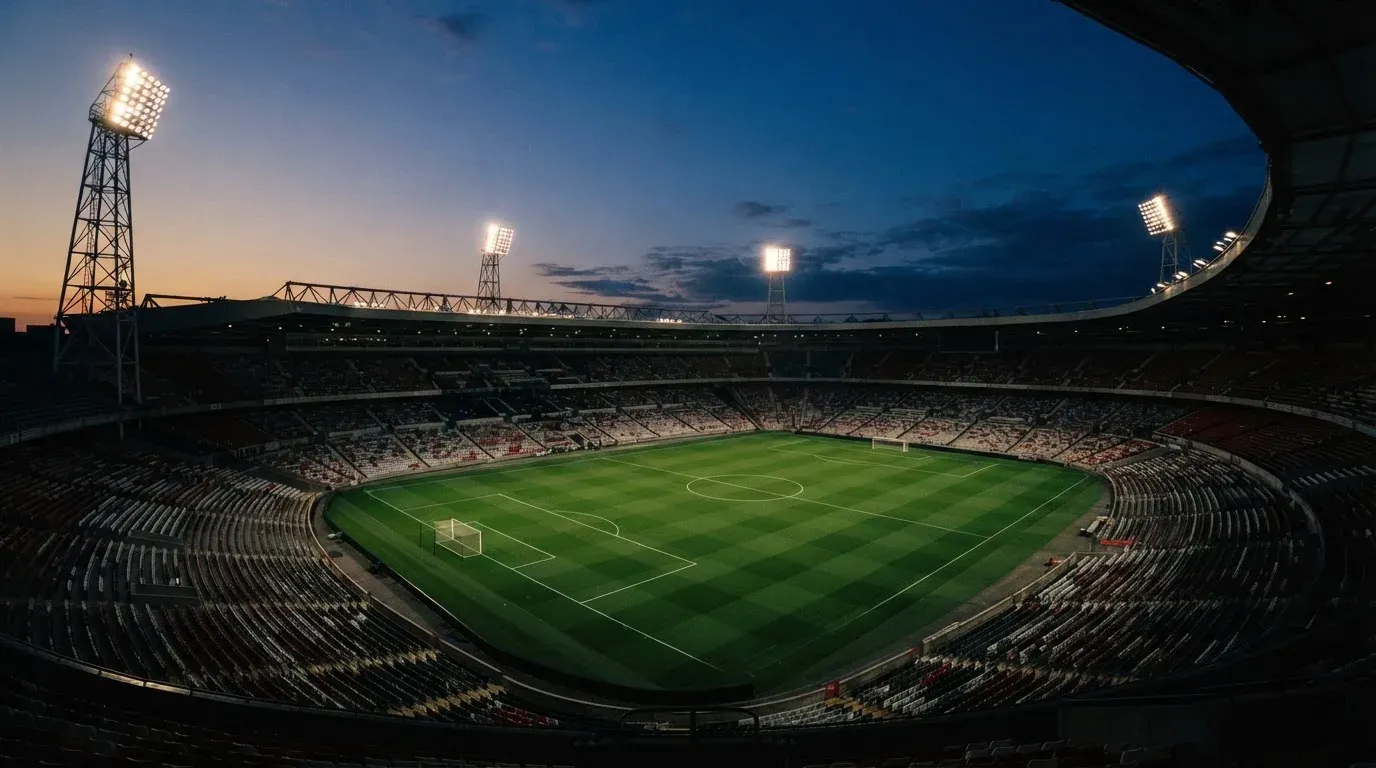An empty football stadium with floodlight masts at dusk