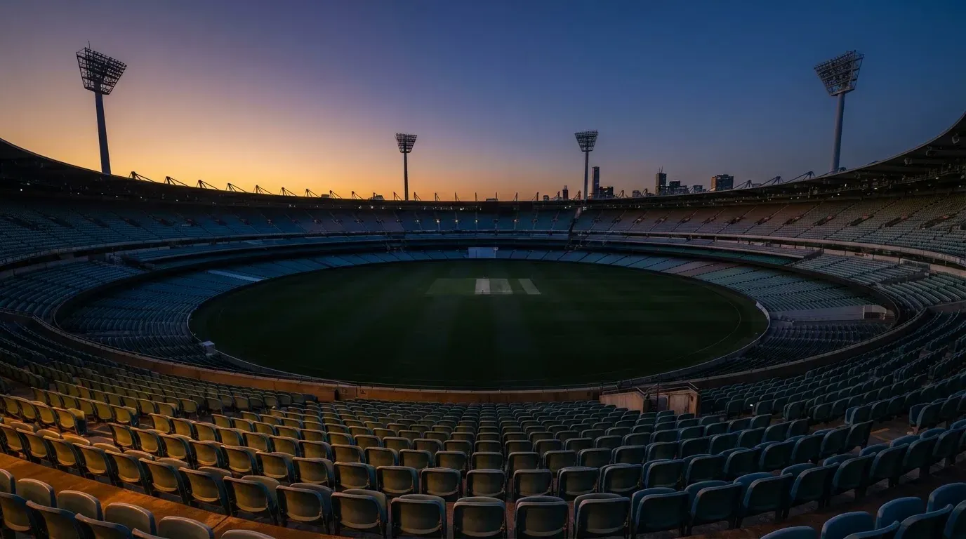 An empty football stadium with floodlight masts at dusk