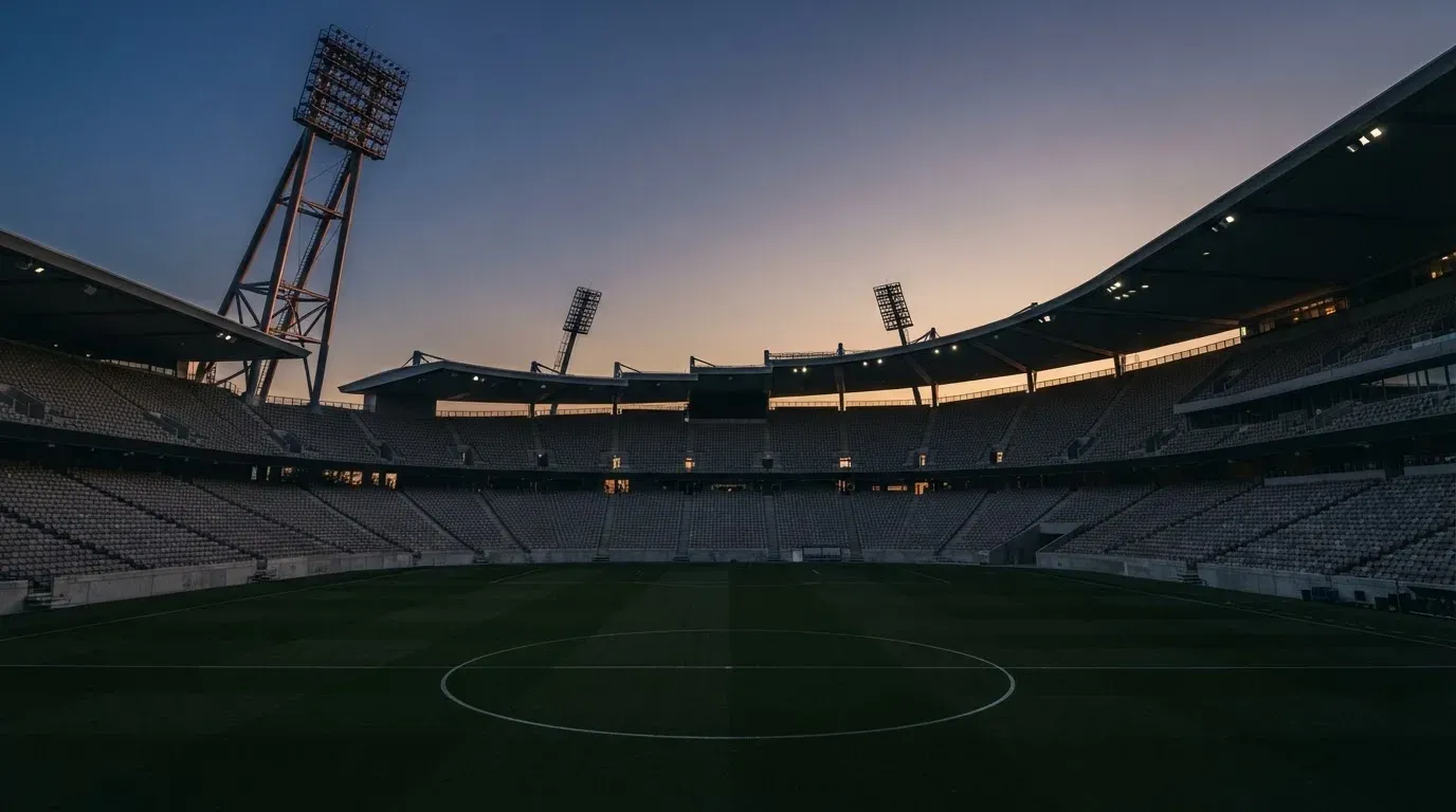 An empty football stadium with floodlight masts at dusk