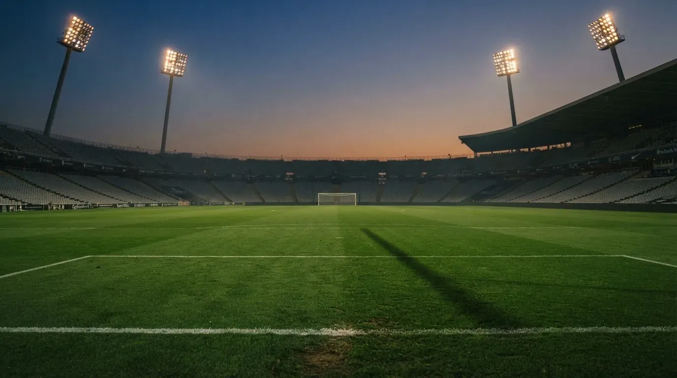 An empty football stadium with floodlight masts at dusk