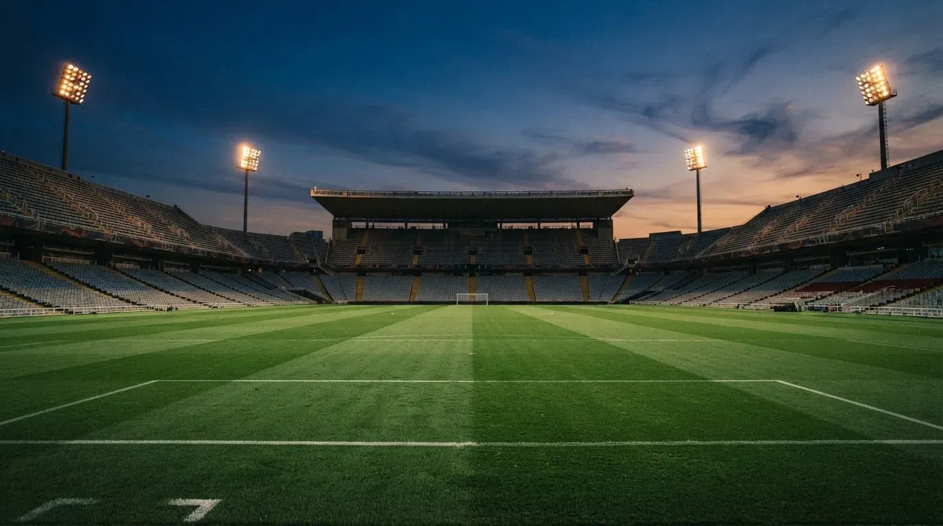An empty football stadium with floodlight masts at dusk