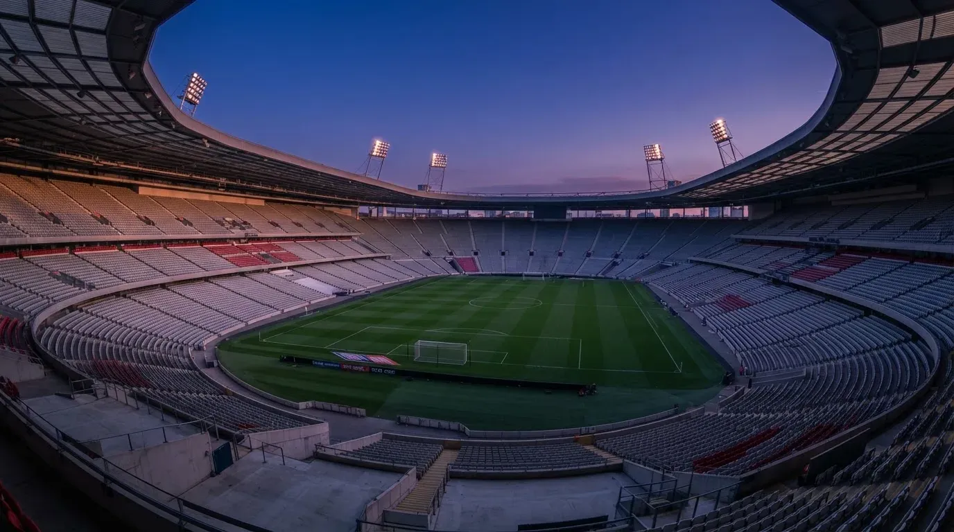An empty football stadium with floodlight masts at dusk