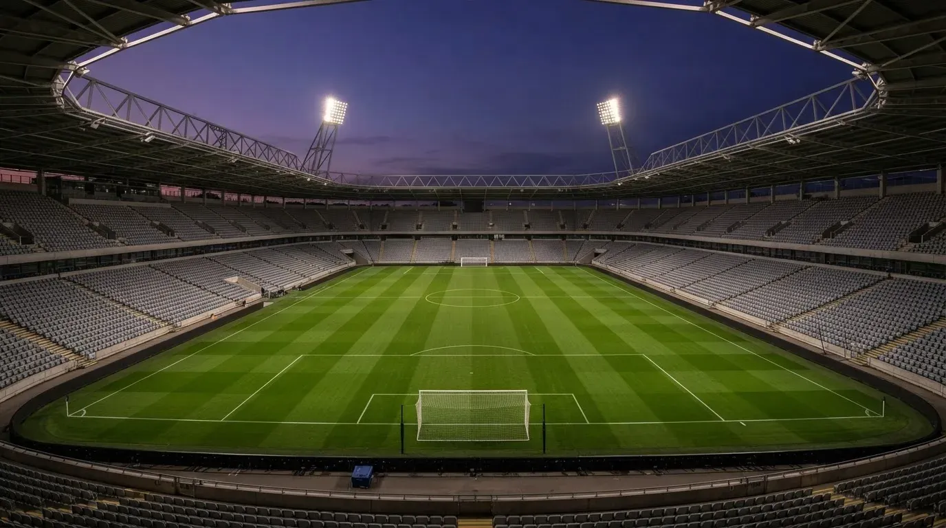 An empty football stadium with floodlight masts at dusk
