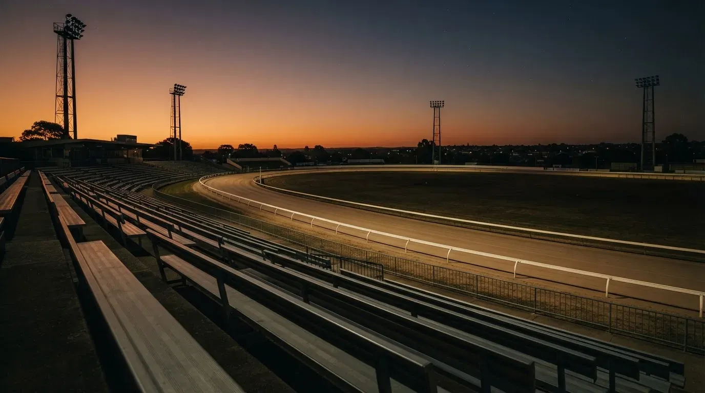 An empty football stadium with floodlight masts at dusk