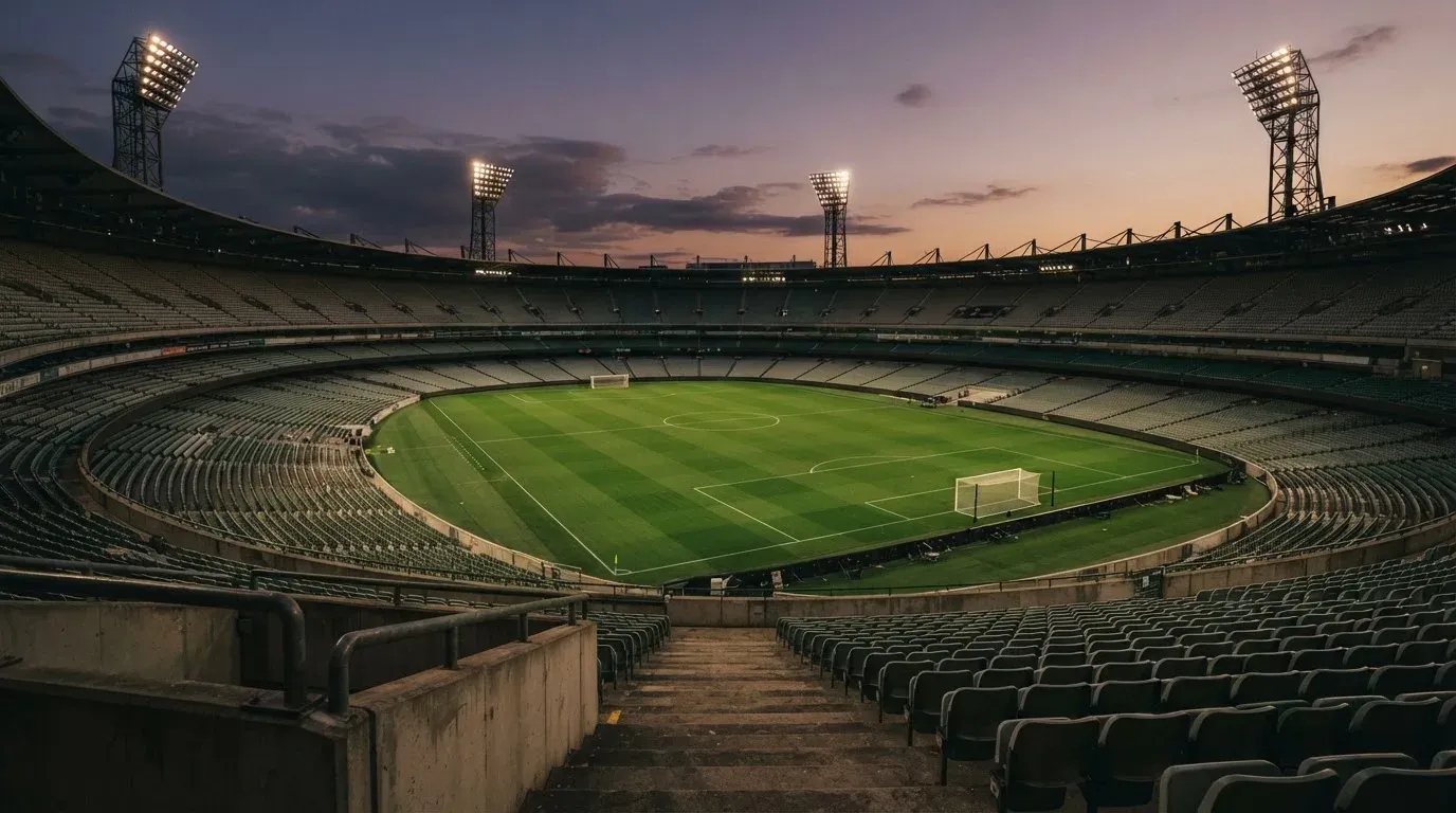 An empty football stadium with floodlight masts at dusk