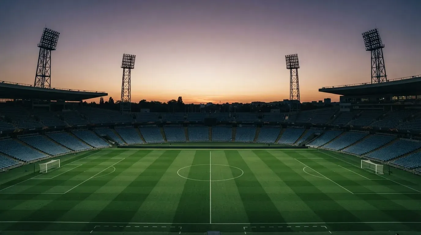 An empty football stadium with floodlight masts at dusk