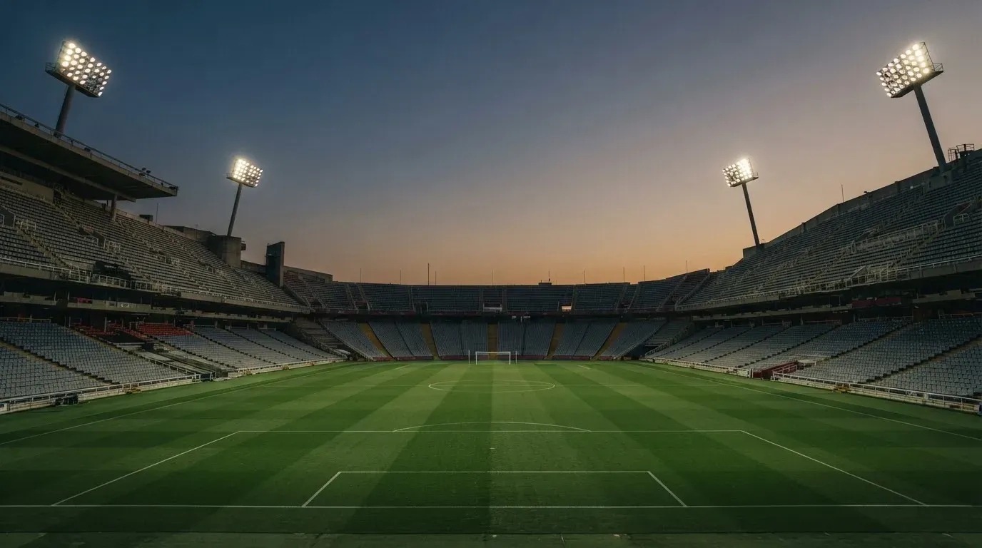 An empty football stadium with floodlight masts at dusk