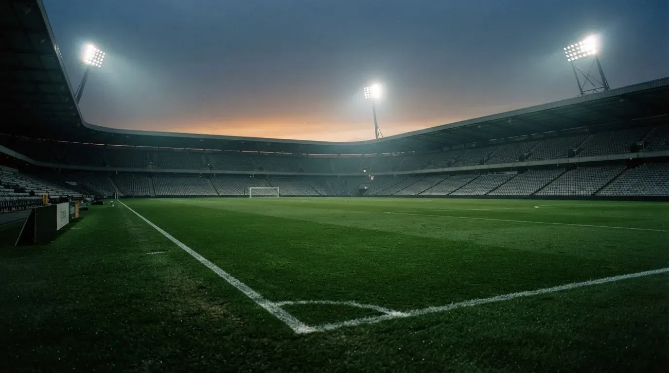 An empty football stadium with floodlight masts at dusk