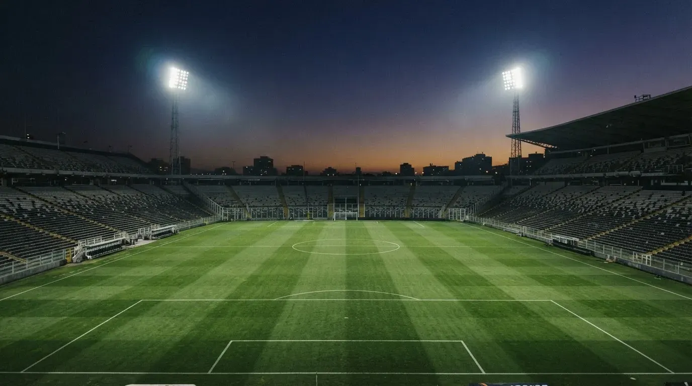 An empty football stadium with floodlight masts at dusk