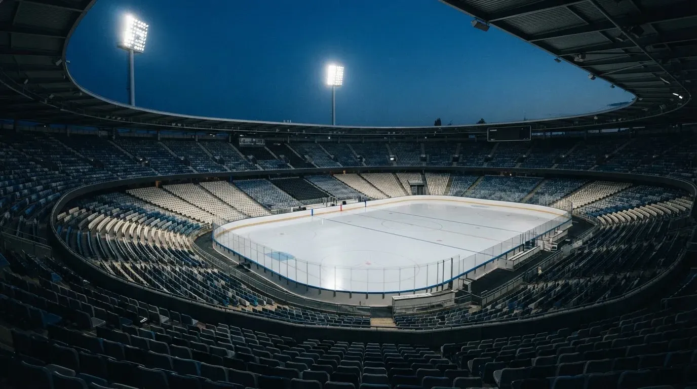 An empty football stadium with floodlight masts at dusk