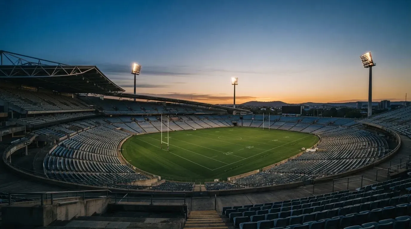 An empty football stadium with floodlight masts at dusk