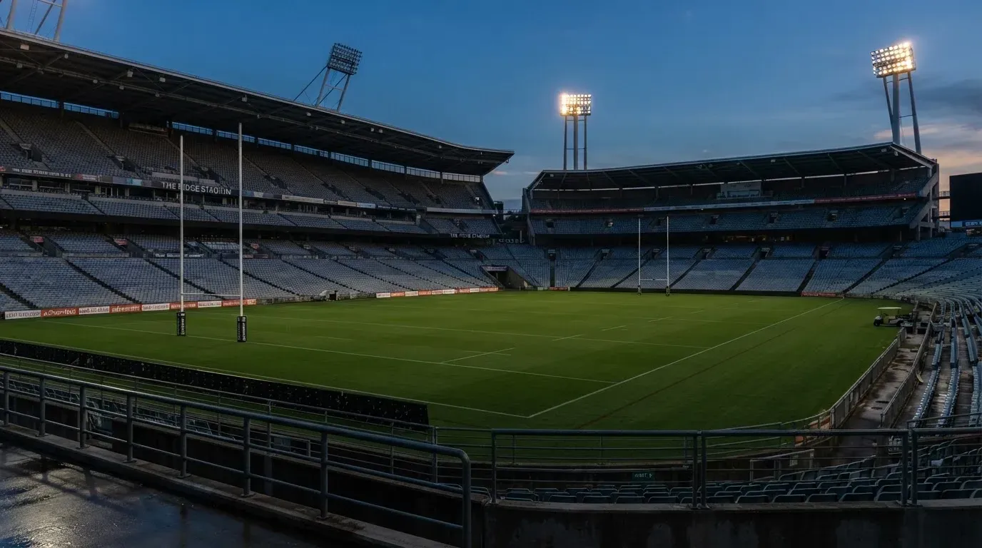 An empty football stadium with floodlight masts at dusk