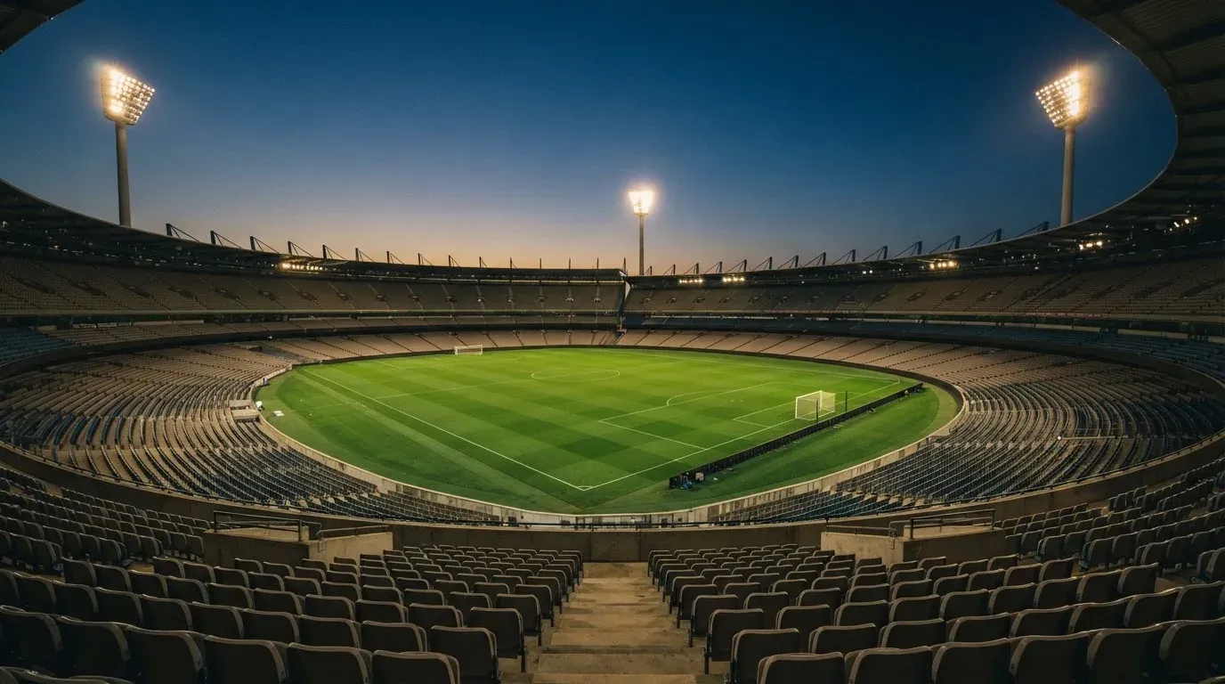 An empty football stadium with floodlight masts at dusk