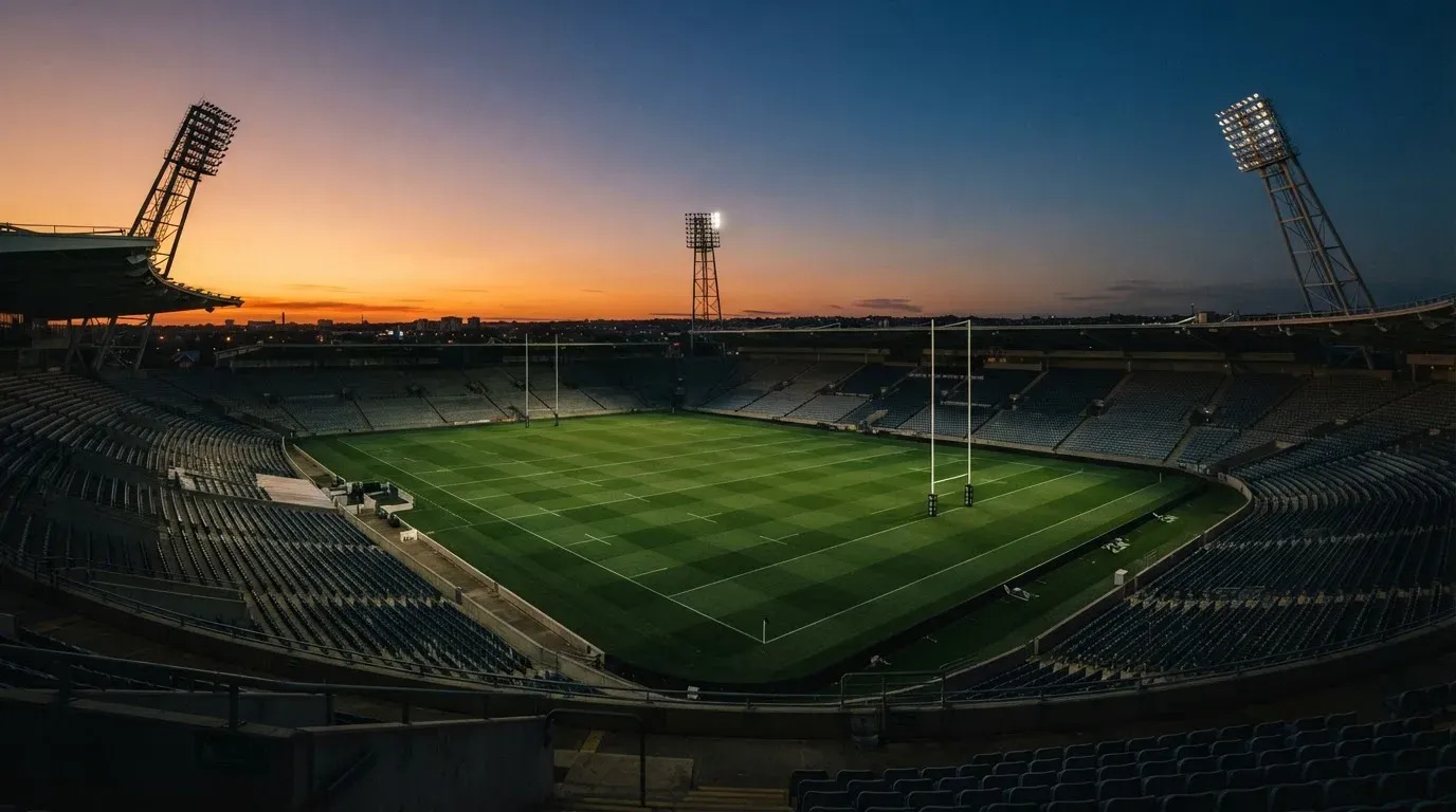 An empty football stadium with floodlight masts at dusk
