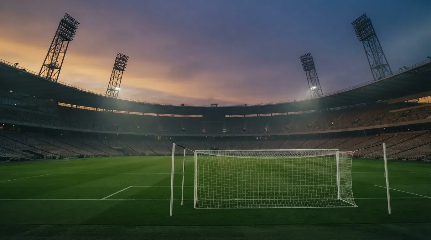 An empty football stadium with floodlight masts at dusk