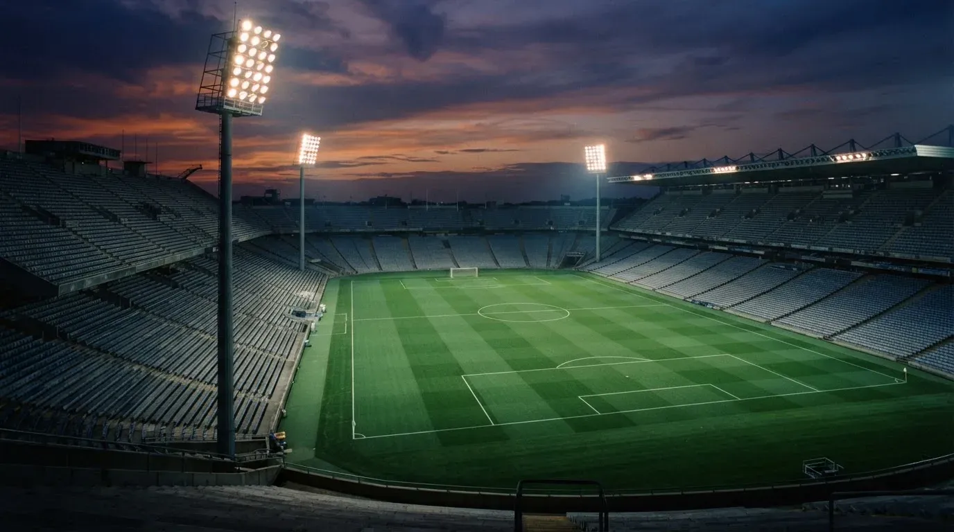 An empty football stadium with floodlight masts at dusk