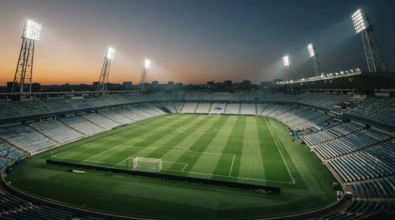 An empty football stadium with floodlight masts at dusk