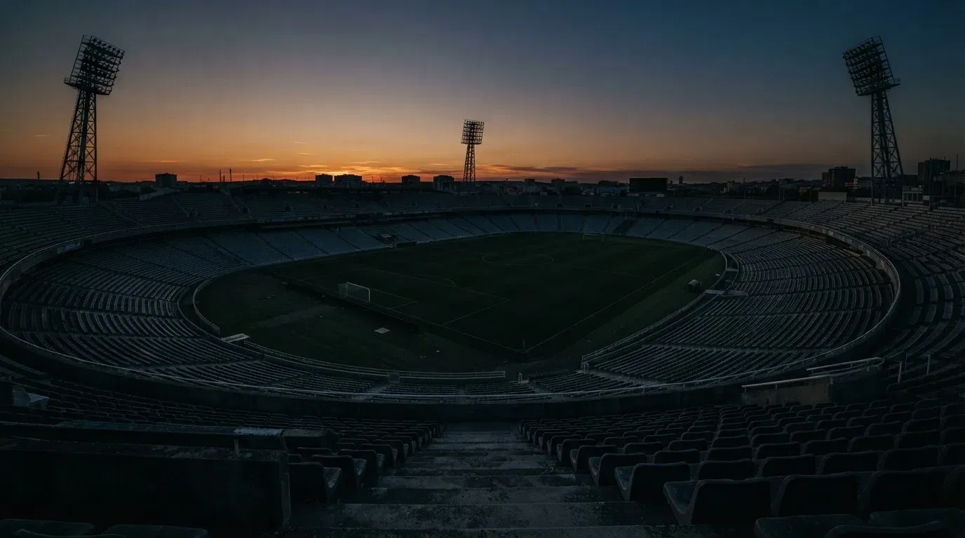An empty football stadium with floodlight masts at dusk