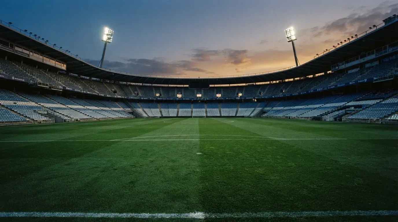 An empty football stadium with floodlight masts at dusk