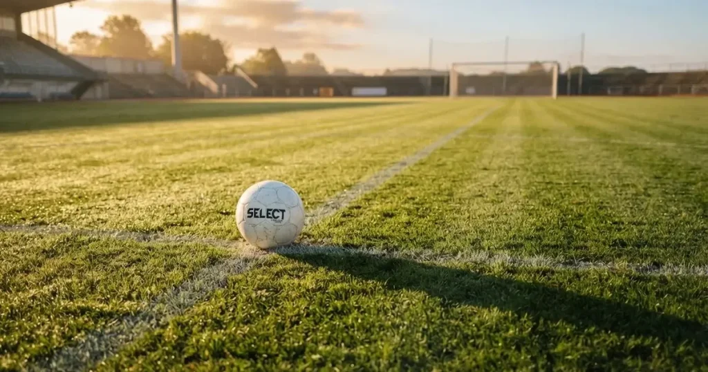 A ball on the centre spot of a grass pitch in morning light