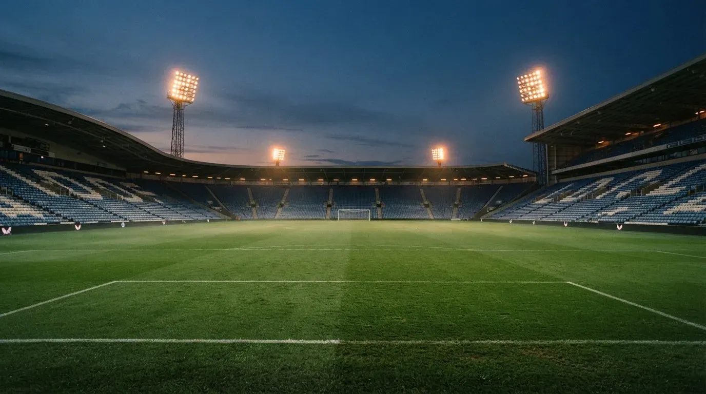 An empty football stadium with floodlight masts at dusk