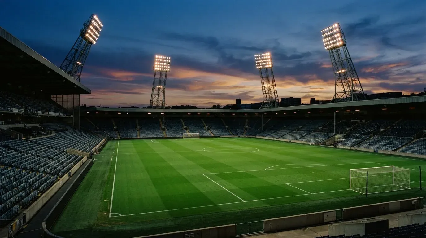 An empty football stadium with floodlight masts at dusk