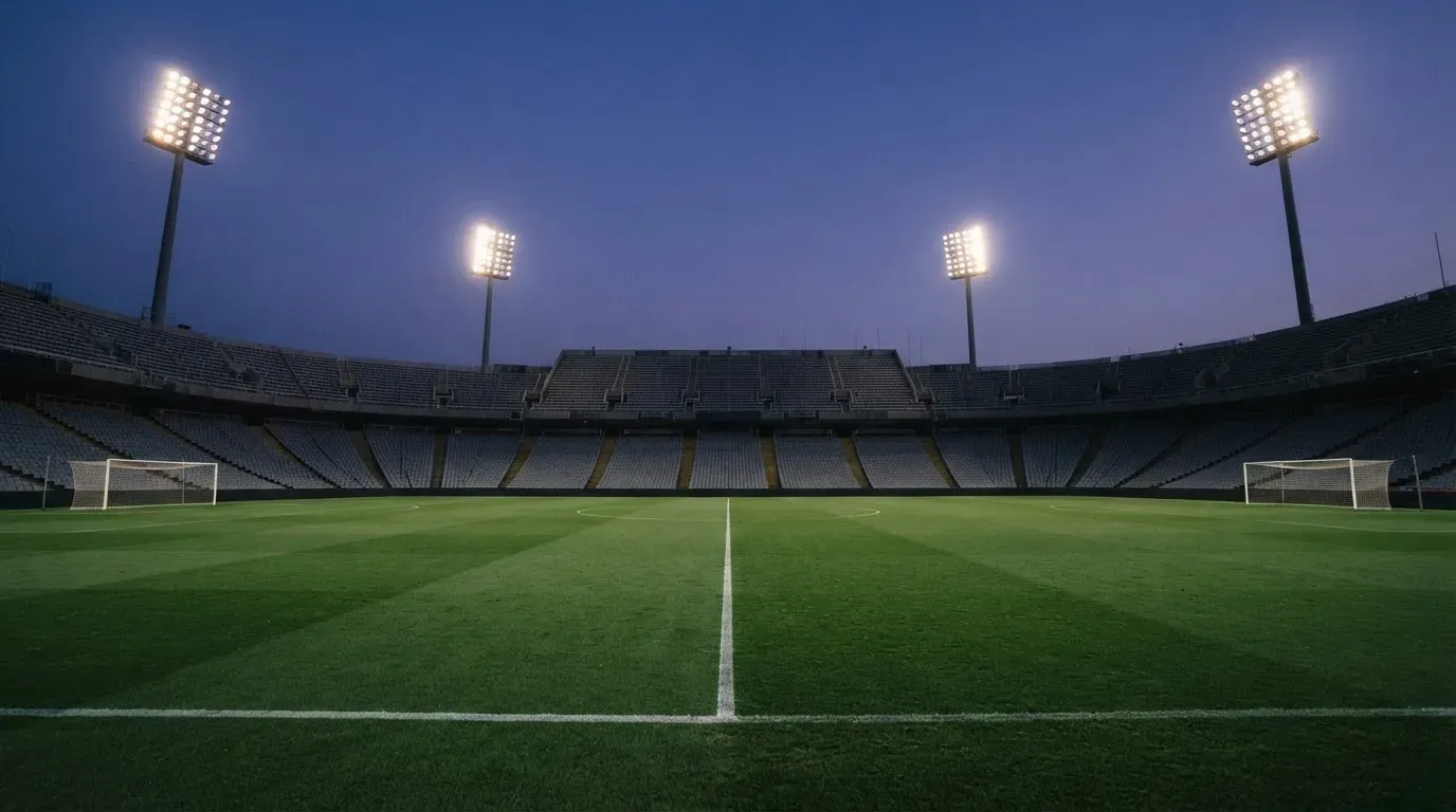 An empty football stadium with floodlight masts at dusk