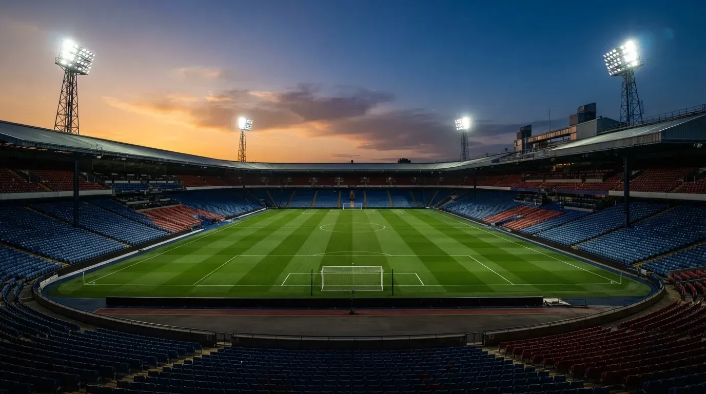 An empty football stadium with floodlight masts at dusk