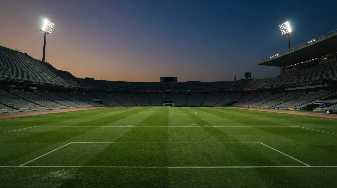 An empty football stadium with floodlight masts at dusk
