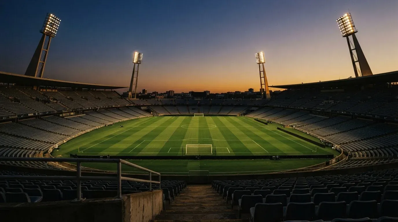 An empty football stadium with floodlight masts at dusk