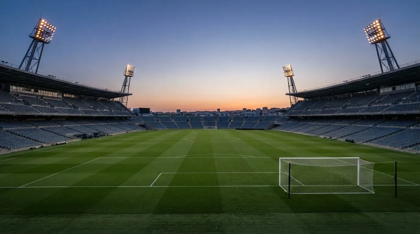 An empty football stadium with floodlight masts at dusk