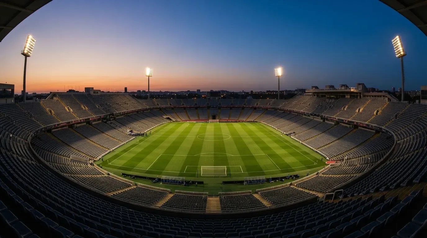 An empty football stadium with floodlight masts at dusk