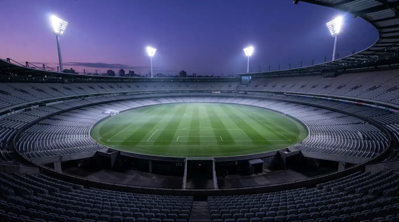 An empty football stadium with floodlight masts at dusk