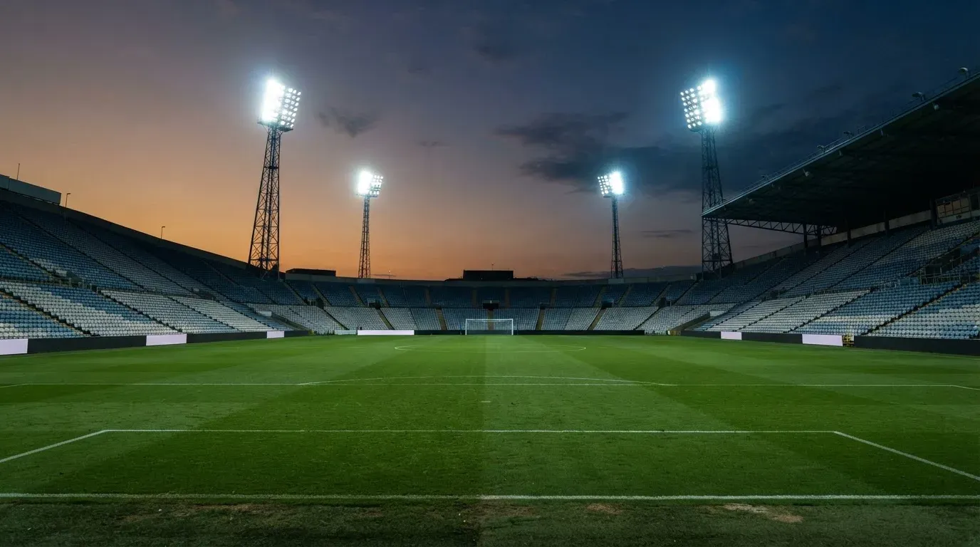 An empty football stadium with floodlight masts at dusk