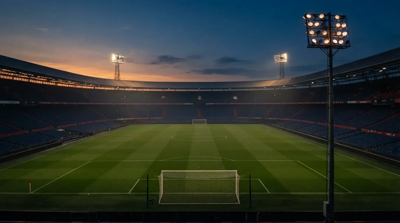 An empty football stadium with floodlight masts at dusk