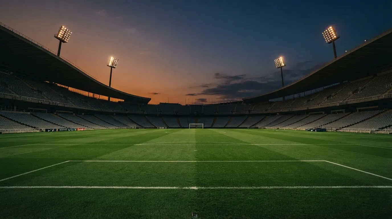 An empty football stadium with floodlight masts at dusk
